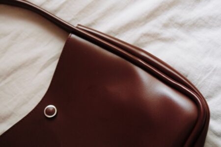 Proenza Schouler’s PS1 Bag Is Quietly Reclaiming the Shoulder Bag A structured leather shoulder bag resting on a neutral surface, showcasing its pebbled texture and buckle detailing
