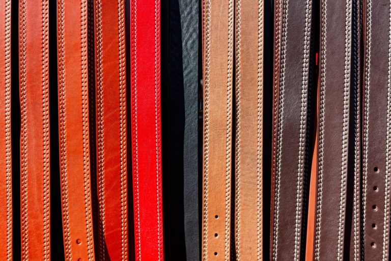 The Slim Belt Is Quietly Reclaiming the Waist From Minimalism A narrow cognac leather belt with simple brass buckle laid flat on a neutral surface