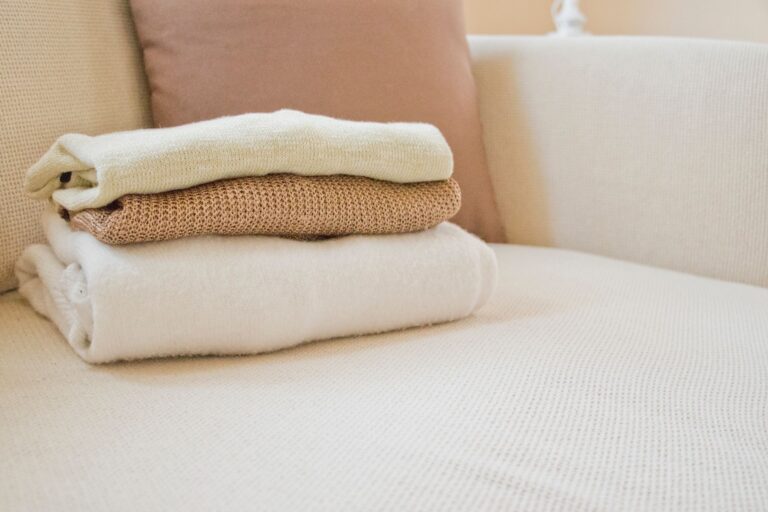 The Cashmere Tank Is Quietly Edging Out the Silk Camisole Neatly folded cashmere knitwear in neutral tones on a white surface