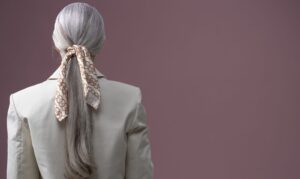 The Slim Scarf Is Quietly Edging Out the Statement Necklace A narrow silk scarf draped loosely around a woman's neck over a simple outfit