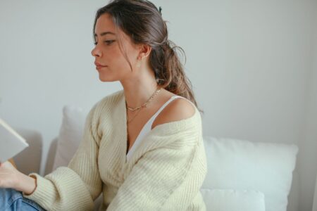Woman wearing a sheer open-knit cardigan layered over a simple tank top