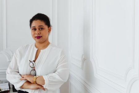 The Gathered Shoulder Blouse Is Quietly Edging Out the Silk Top Woman wearing a white gathered shoulder blouse styled with tailored trousers