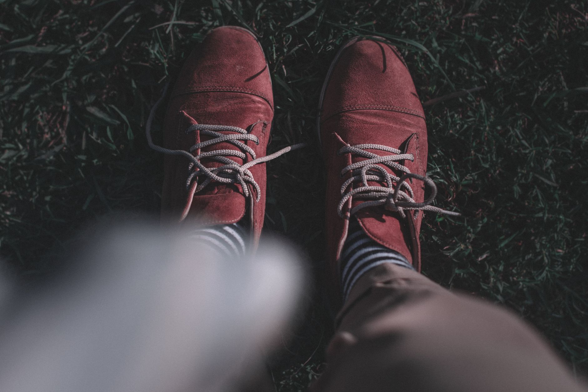 Close-up of a pair of minimalist suede slip-on shoes on a neutral background