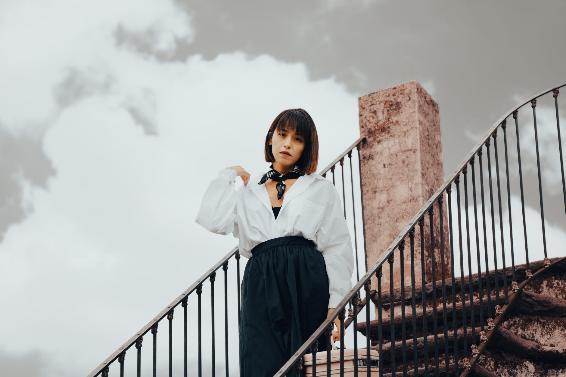 A woman wearing a draped scarf-style jacket in a neutral colorway, styled with simple trousers