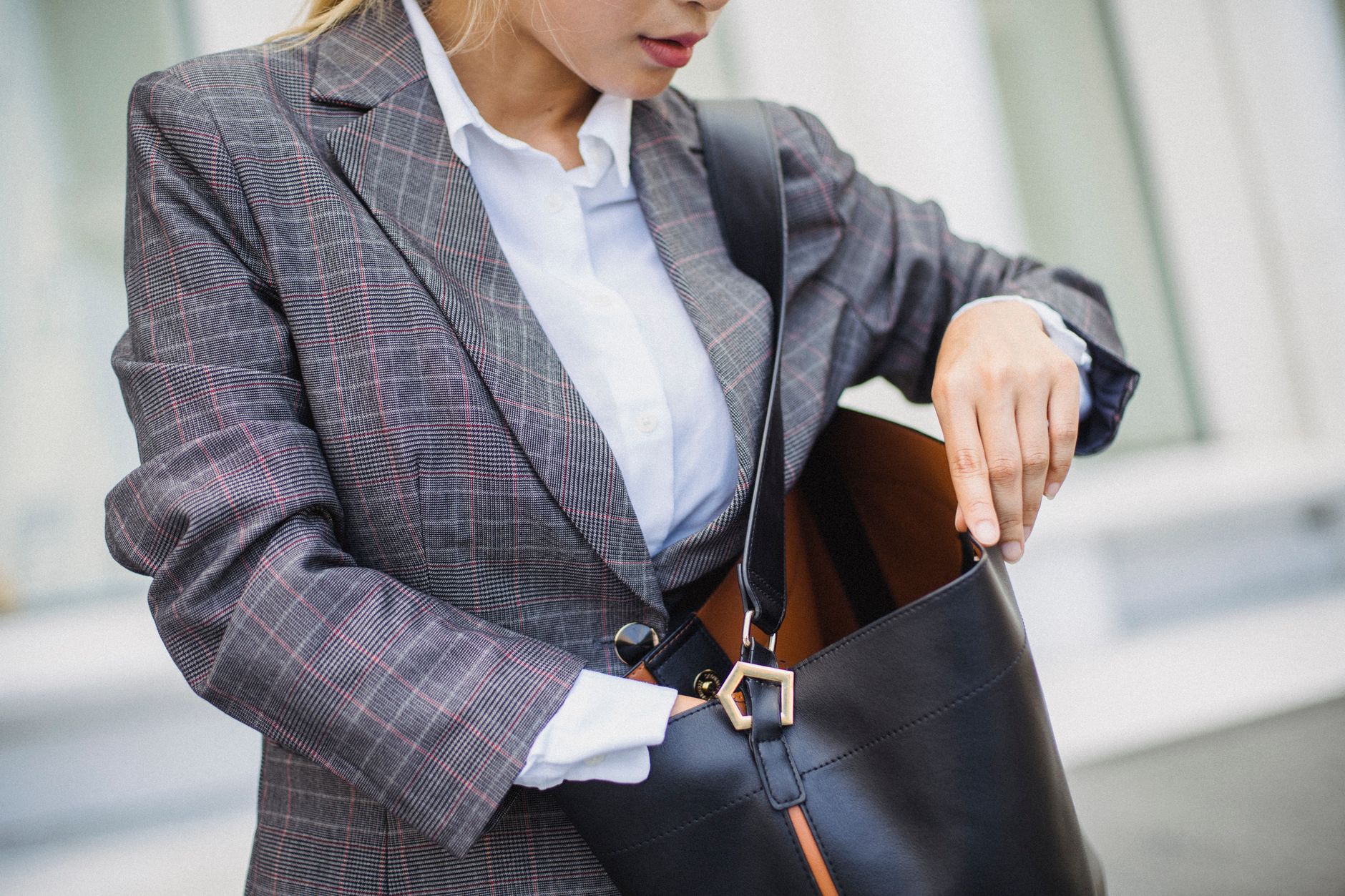 A stylish woman carrying a small structured handbag in a minimal outfit
