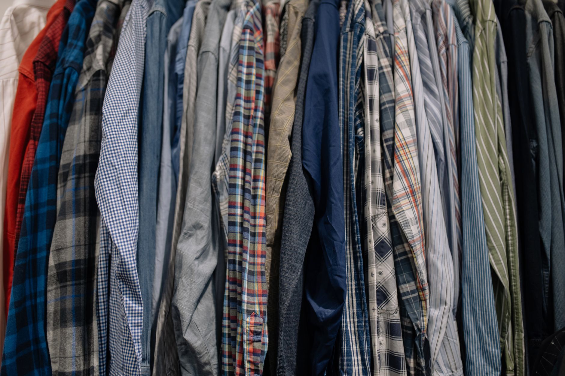 Close-up of structured shirt fabric and collar detail hanging in a wardrobe