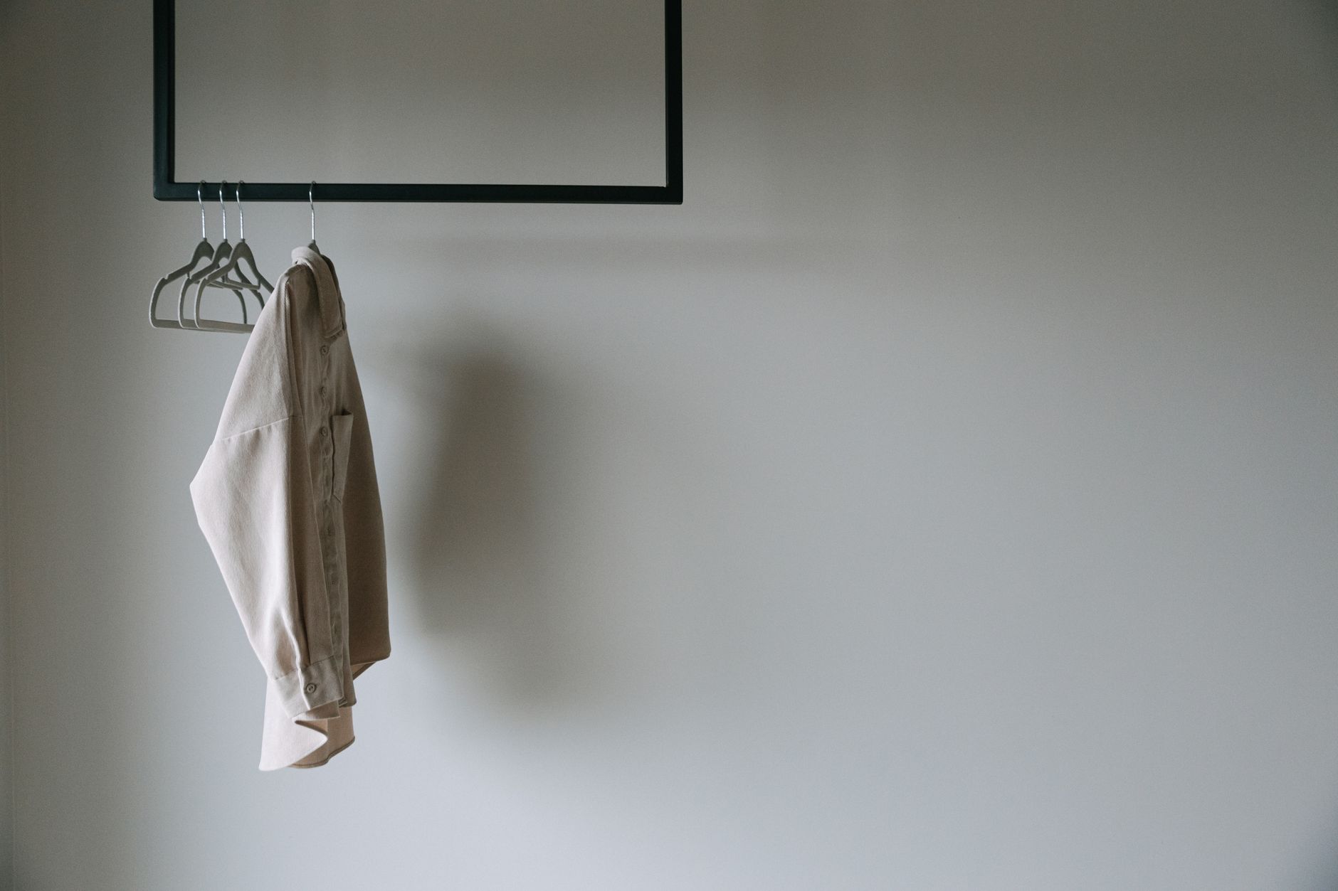 Neatly arranged minimal wardrobe with neutral-toned shirts on hangers