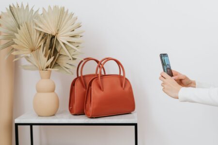 The Trapeze Bag Is Quietly Edging Out the Structured Top Handle A trapeze-shaped leather handbag with a triangular silhouette resting on a neutral surface