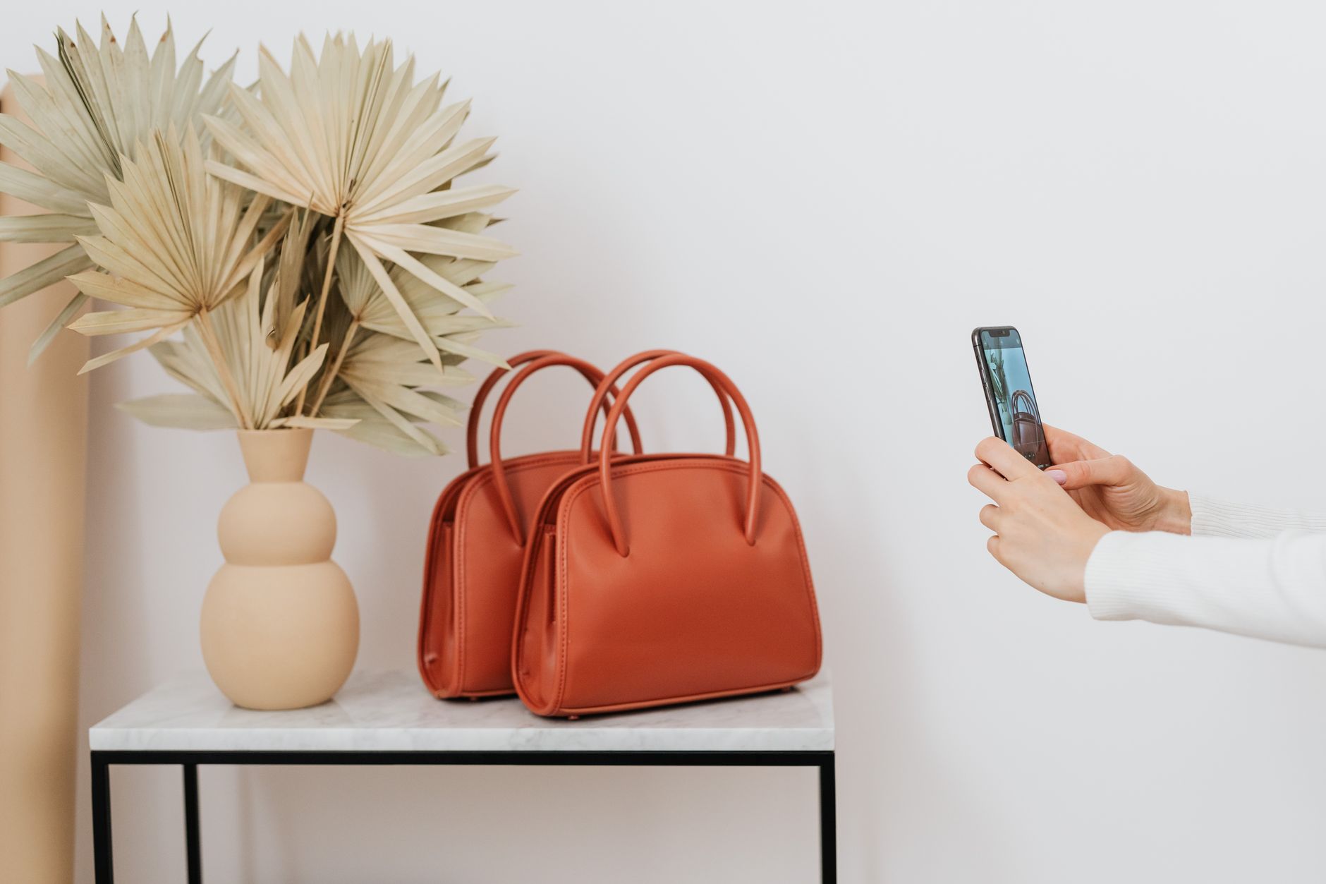 A trapeze-shaped leather handbag with a triangular silhouette resting on a neutral surface