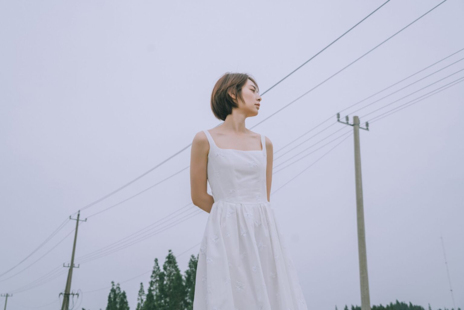 A white broderie anglaise dress with eyelet embroidery detail hanging on a rack