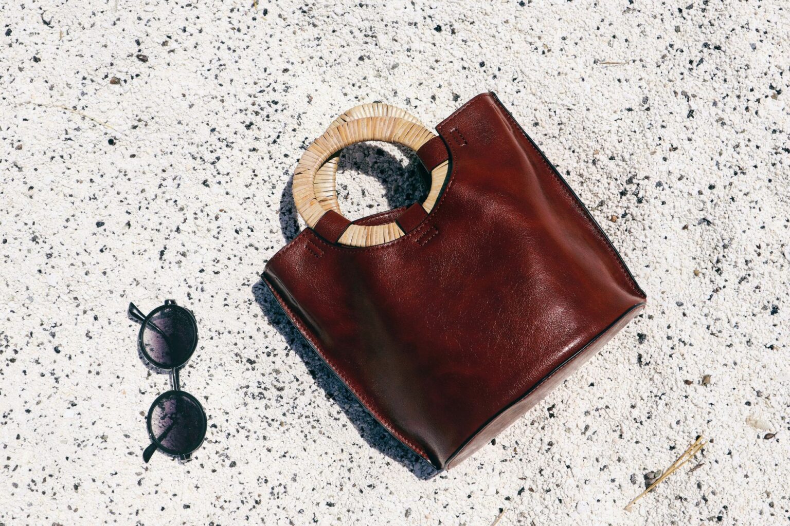 A woven raffia clutch bag on a neutral surface, showing natural fiber texture and detail