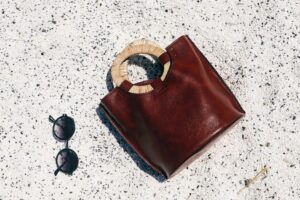 The Raffia Clutch Is Quietly Edging Out the Evening Minaudière A woven raffia clutch bag on a neutral surface, showing natural fiber texture and detail
