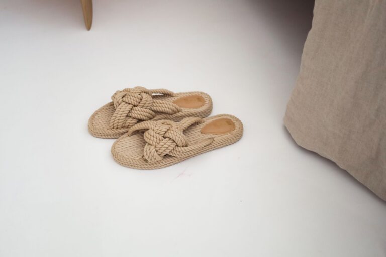 The Raffia Flat Is Quietly Edging Out the Leather Sandal Close-up of woven raffia flat sandals on a light surface