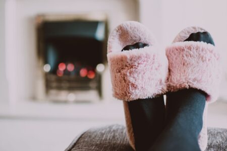 The Draped Slipper Is Quietly Edging Out the Embellished Mule Close-up of draped fabric slipper shoes in neutral satin on a wooden surface