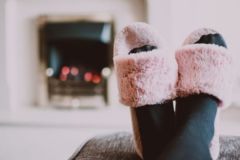 The Draped Slipper Is Quietly Edging Out the Embellished Mule Close-up of draped fabric slipper shoes in neutral satin on a wooden surface