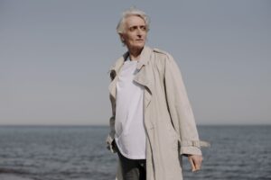 A white structured trench coat displayed on a model against a neutral background
