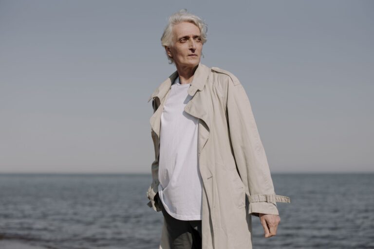 The Broderie Anglaise Trench Is Quietly Edging Out the Cotton Mac A white structured trench coat displayed on a model against a neutral background