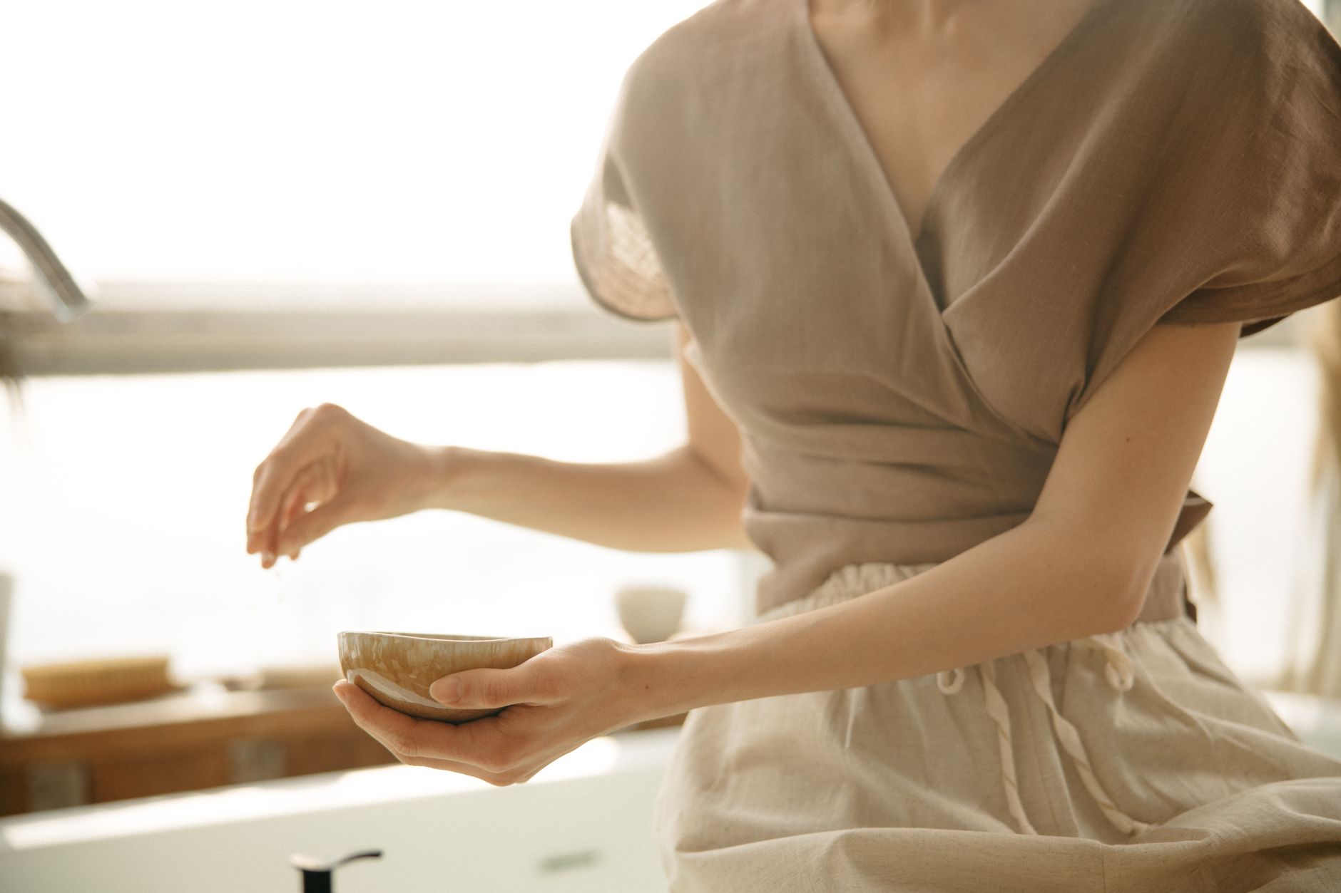 A woman wearing a textured white linen blouse styled with tailored trousers