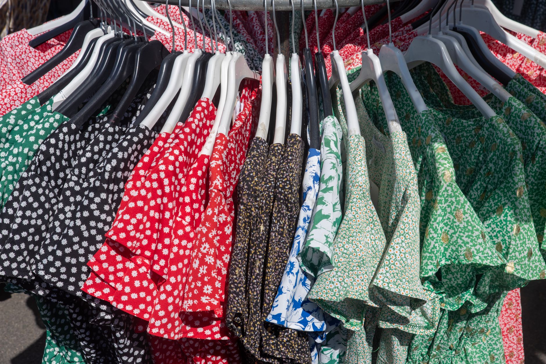 Clothing rack displaying white and off-white summer dresses in a boutique setting