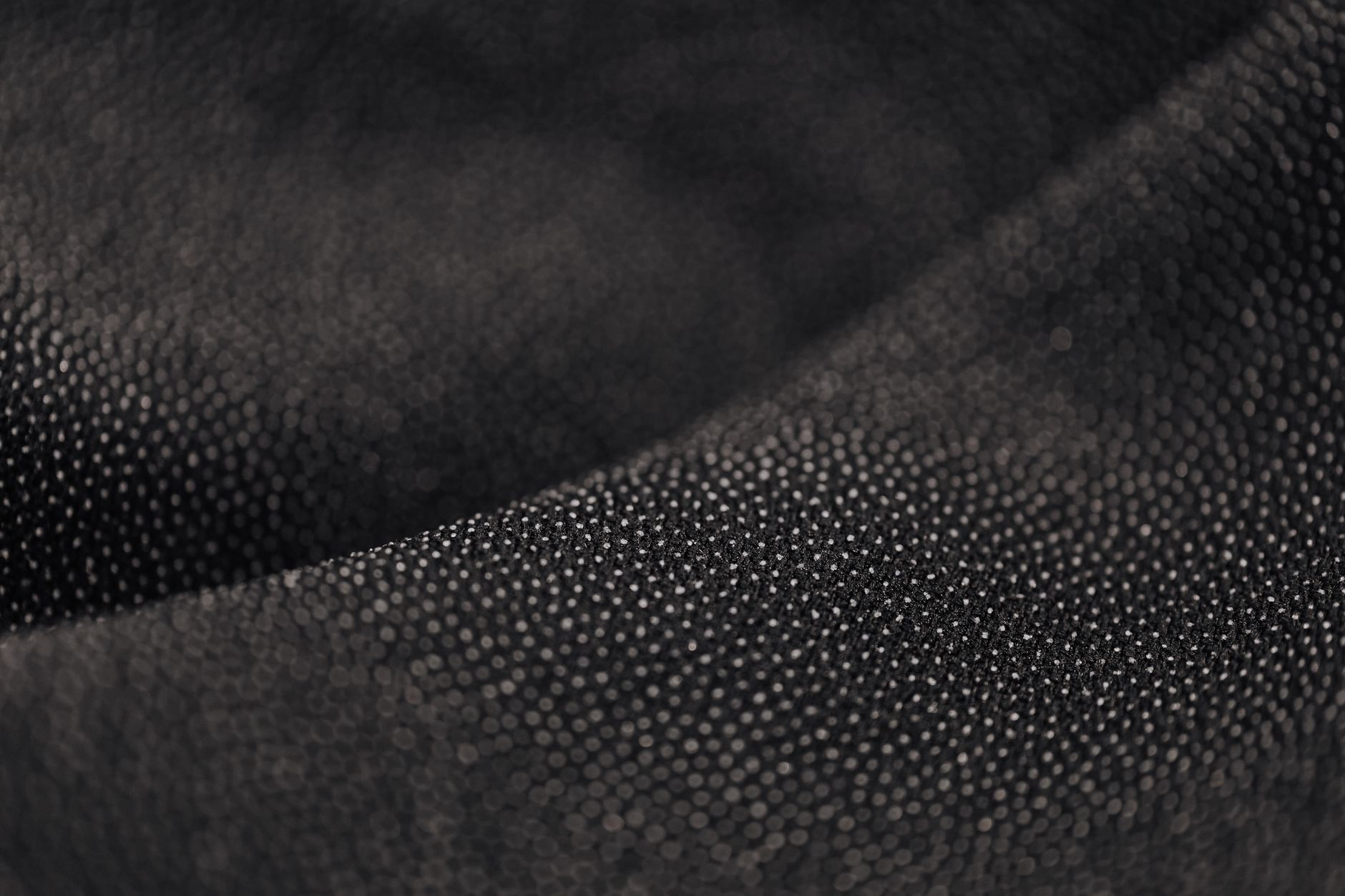 Fabric detail showing deliberate contrast-stitch seam on a structured garment