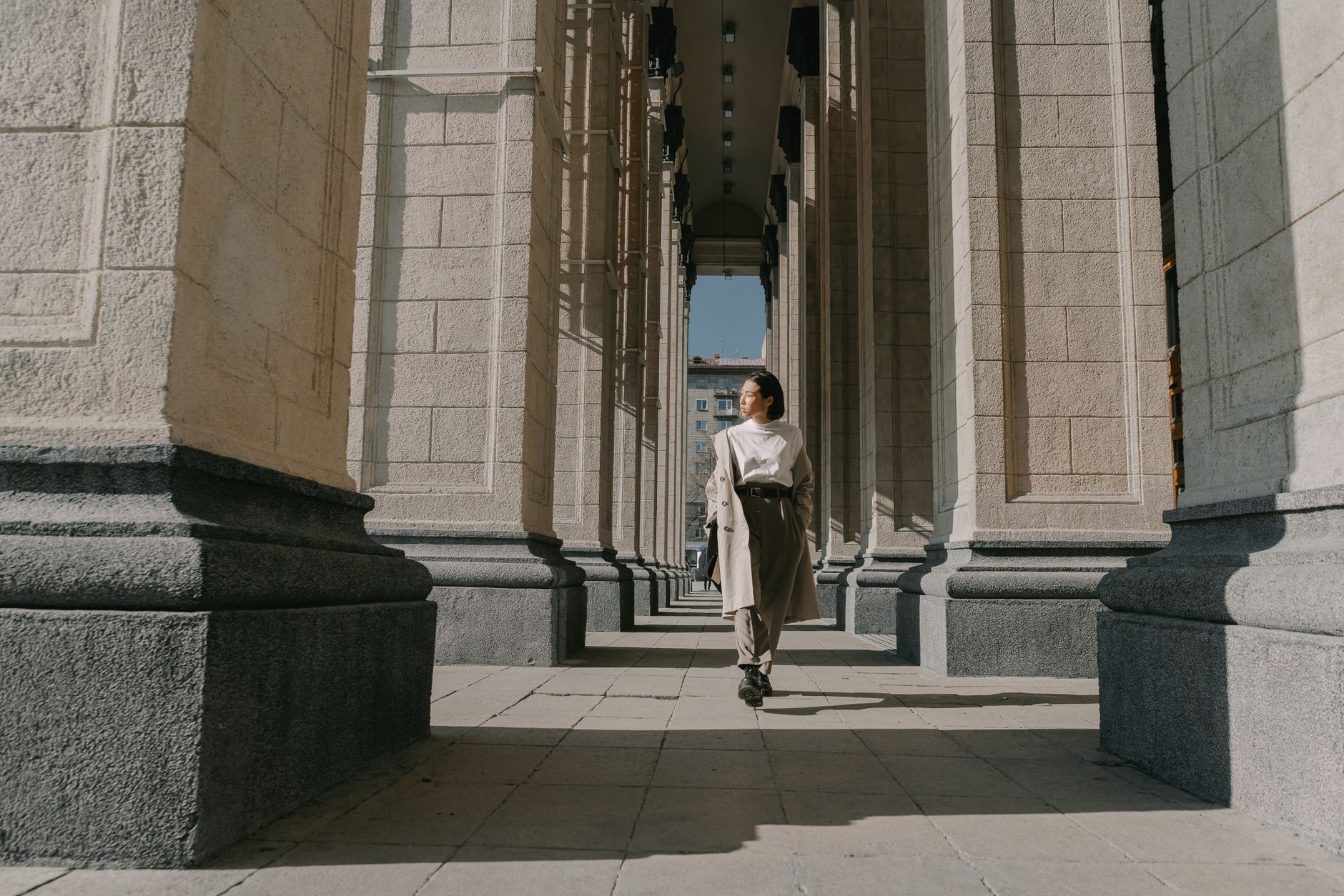 A person wearing a light-colored coat styled with simple basics on a city street