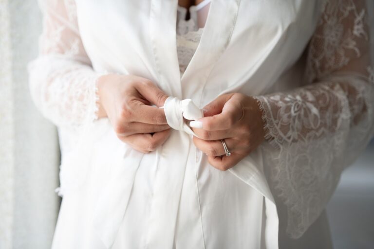 The Broderie Anglaise Coat Is Quietly Edging Out the Trench Coat A white broderie anglaise coat hanging on a boutique rail, showing delicate eyelet fabric detail