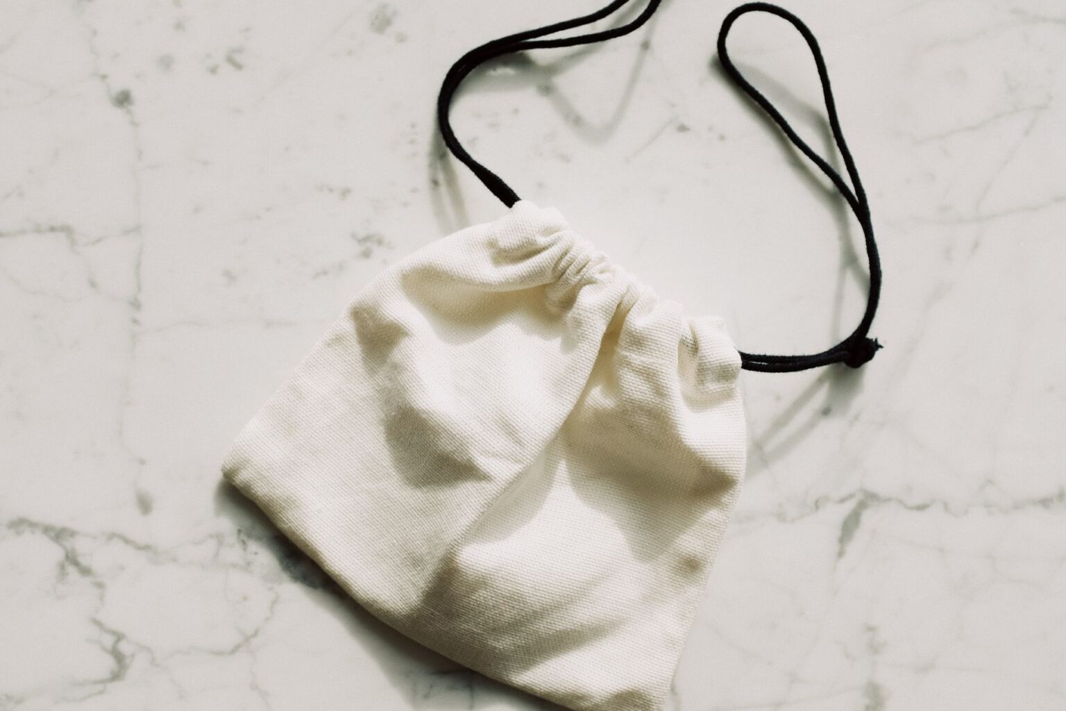 The Broderie Anglaise Bag Is Quietly Edging Out the Straw Clutch A white broderie anglaise fabric bag with eyelet embroidery detail on a light background