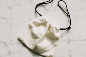 The Broderie Anglaise Bag Is Quietly Edging Out the Straw Clutch A white broderie anglaise fabric bag with eyelet embroidery detail on a light background