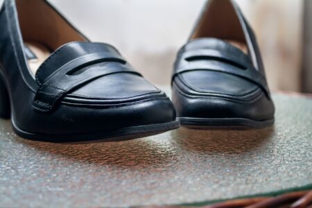 Close-up of a pair of low-heeled clogs in neutral leather on a clean surface