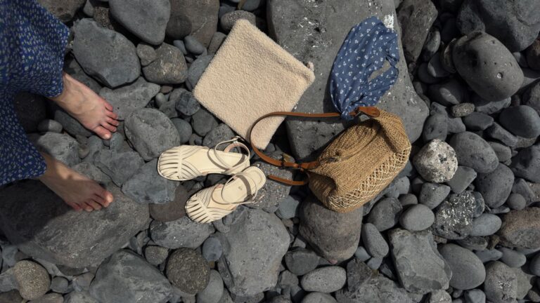 The Grosgrain Trim Sandal Is Quietly Edging Out the Ribbon Flat Close-up flat lay of women's sandals with fabric trim detailing on a neutral surface