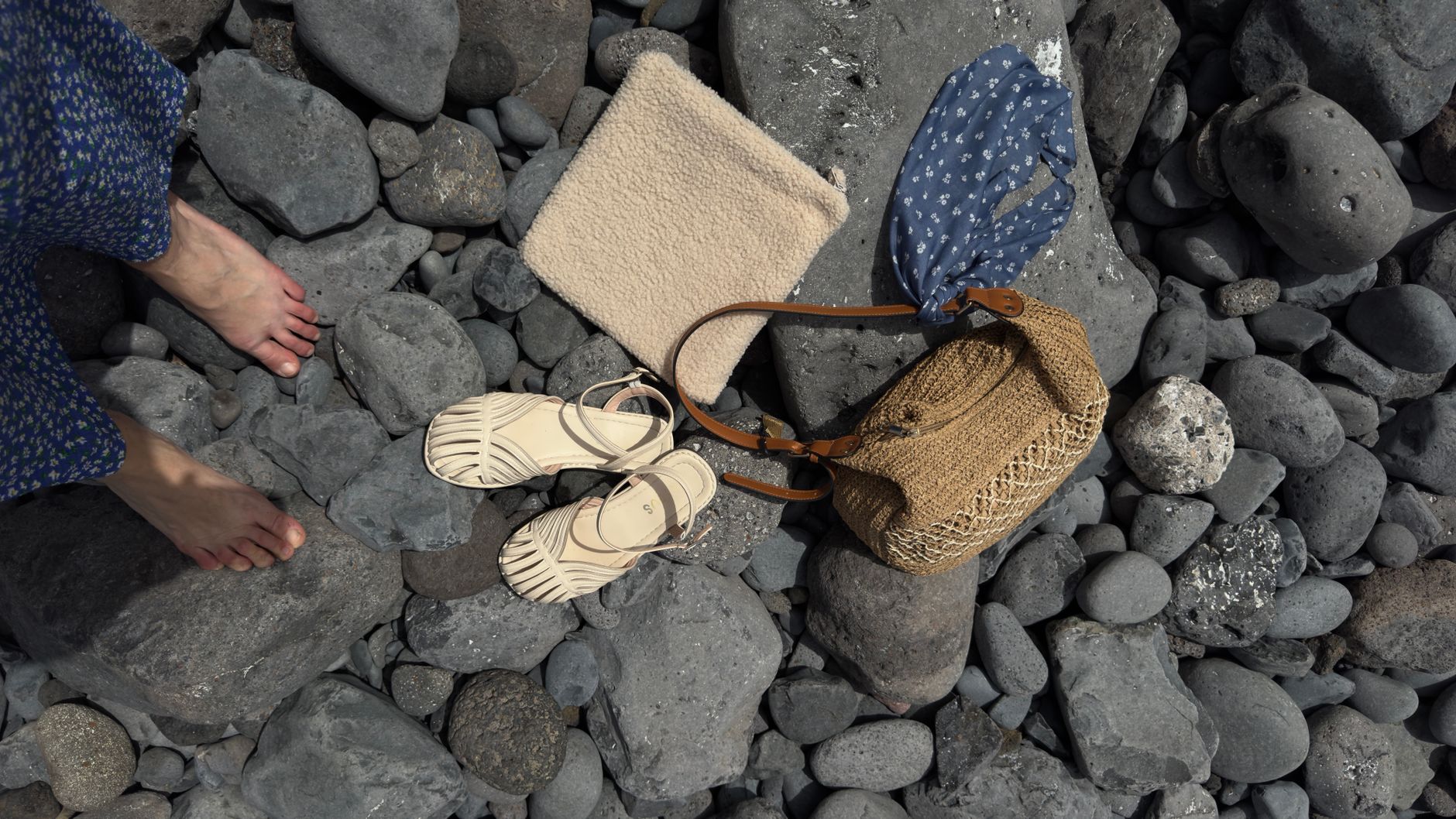 Close-up flat lay of women's sandals with fabric trim detailing on a neutral surface