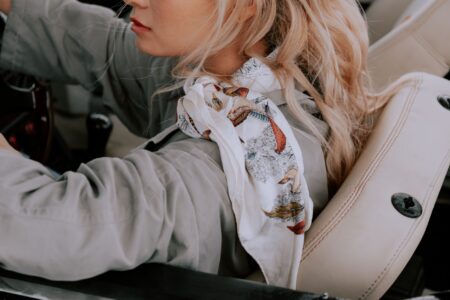 The Tube Scarf Is Quietly Edging Out the Silk Neckerchief Close-up of a person wearing a fitted tube scarf in a neutral tone with a structured coat