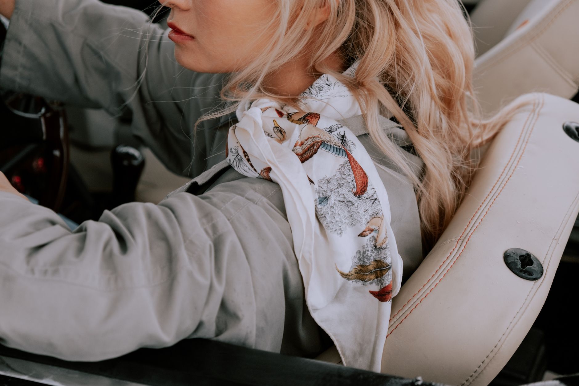Close-up of a person wearing a fitted tube scarf in a neutral tone with a structured coat