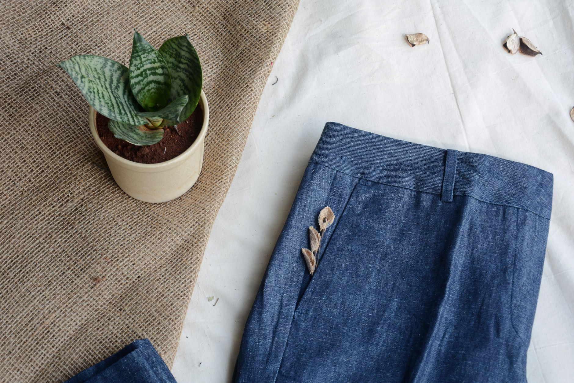 Neatly folded linen trousers in neutral earth tones on a white surface