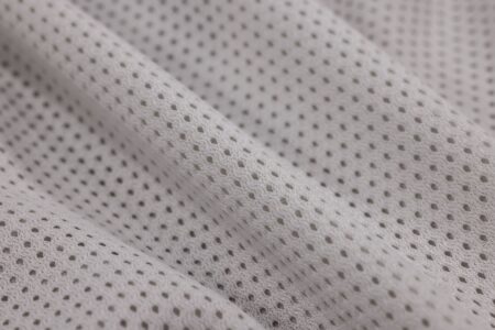 The Broderie Anglaise Trouser Is Quietly Edging Out the Linen Wide-Leg Close-up of white broderie anglaise cotton fabric showing delicate embroidered cutwork pattern