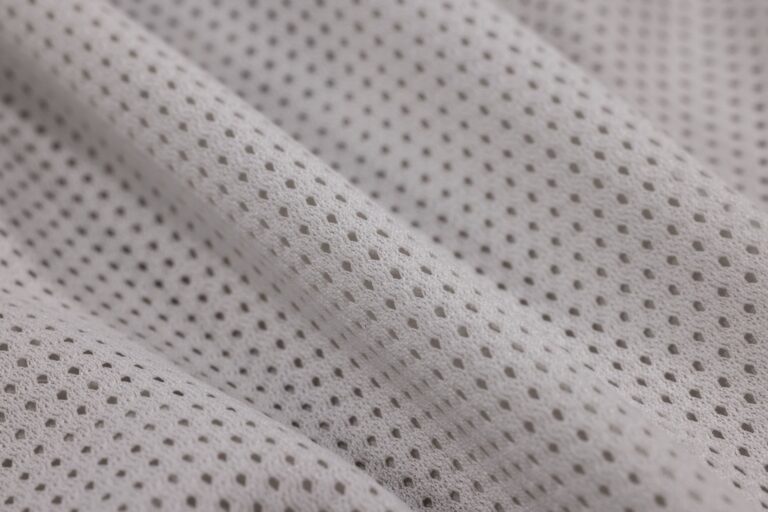 The Broderie Anglaise Trouser Is Quietly Edging Out the Linen Wide-Leg Close-up of white broderie anglaise cotton fabric showing delicate embroidered cutwork pattern