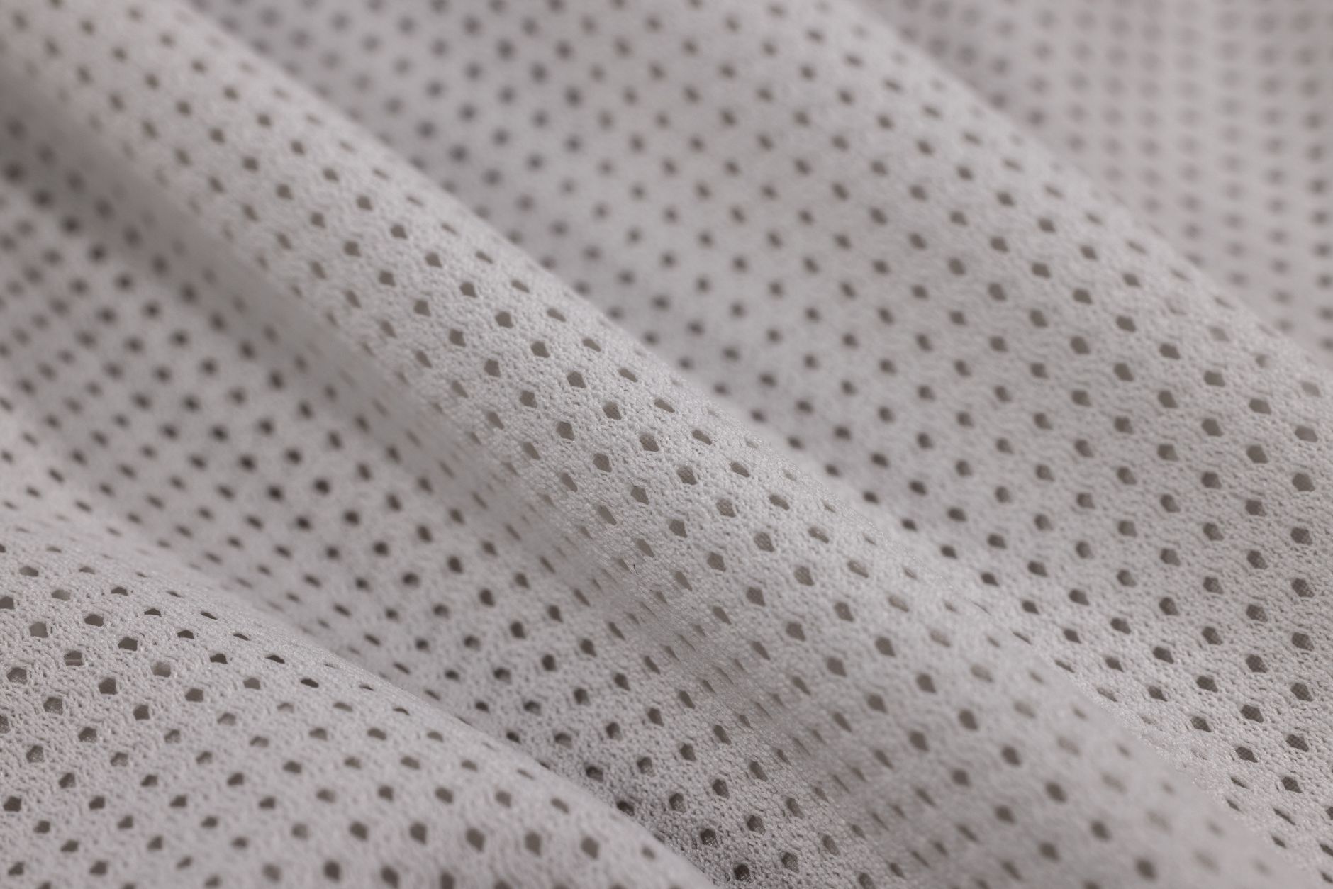 Close-up of white broderie anglaise cotton fabric showing delicate embroidered cutwork pattern