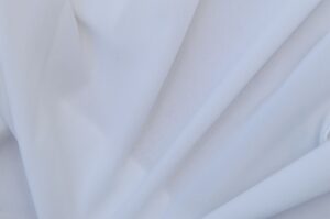 The Broderie Anglaise Cardigan Is Quietly Edging Out the Cotton Knit Close-up of broderie anglaise fabric with delicate eyelet embroidery detail