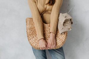 A structured raffia clutch bag with intricate weave detail on a neutral background