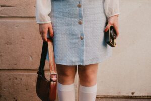 The Tweed Micro-Bag Is Quietly Edging Out the Leather Belt Bag A small structured tweed micro-bag with a gold chain strap against a neutral background
