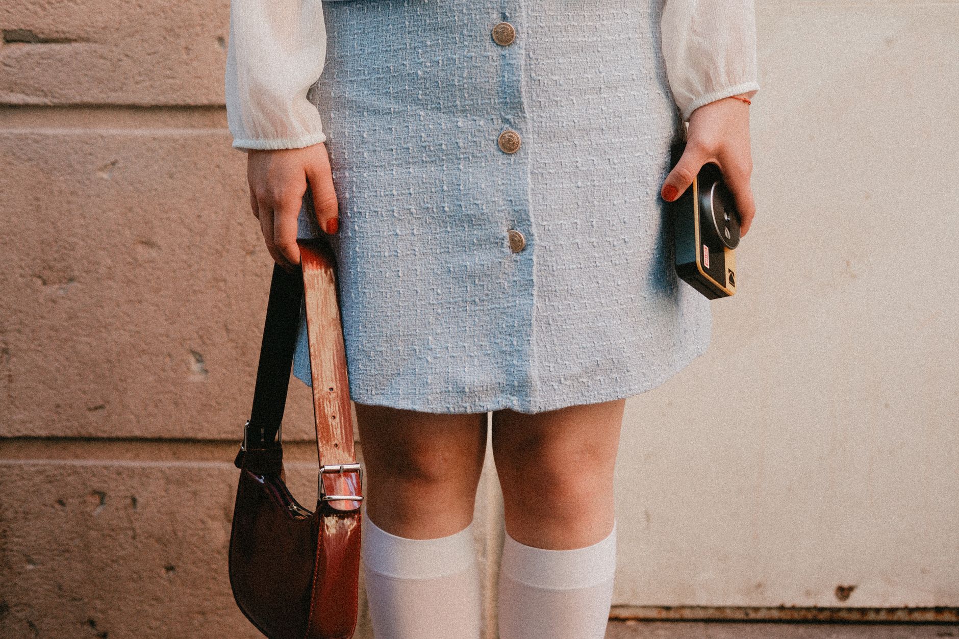 A small structured tweed micro-bag with a gold chain strap against a neutral background