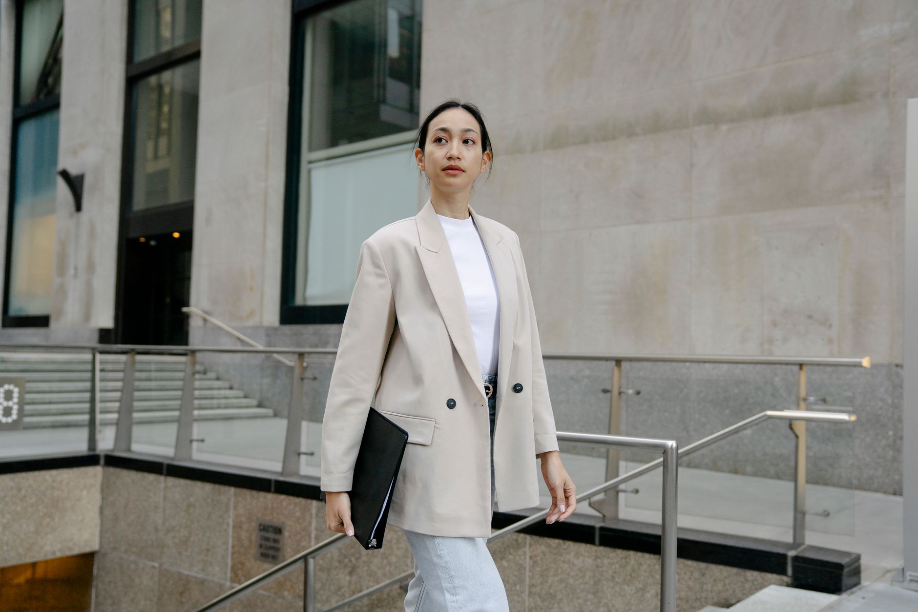 A person wearing a light linen blazer over a simple outfit with tailored trousers and loafers