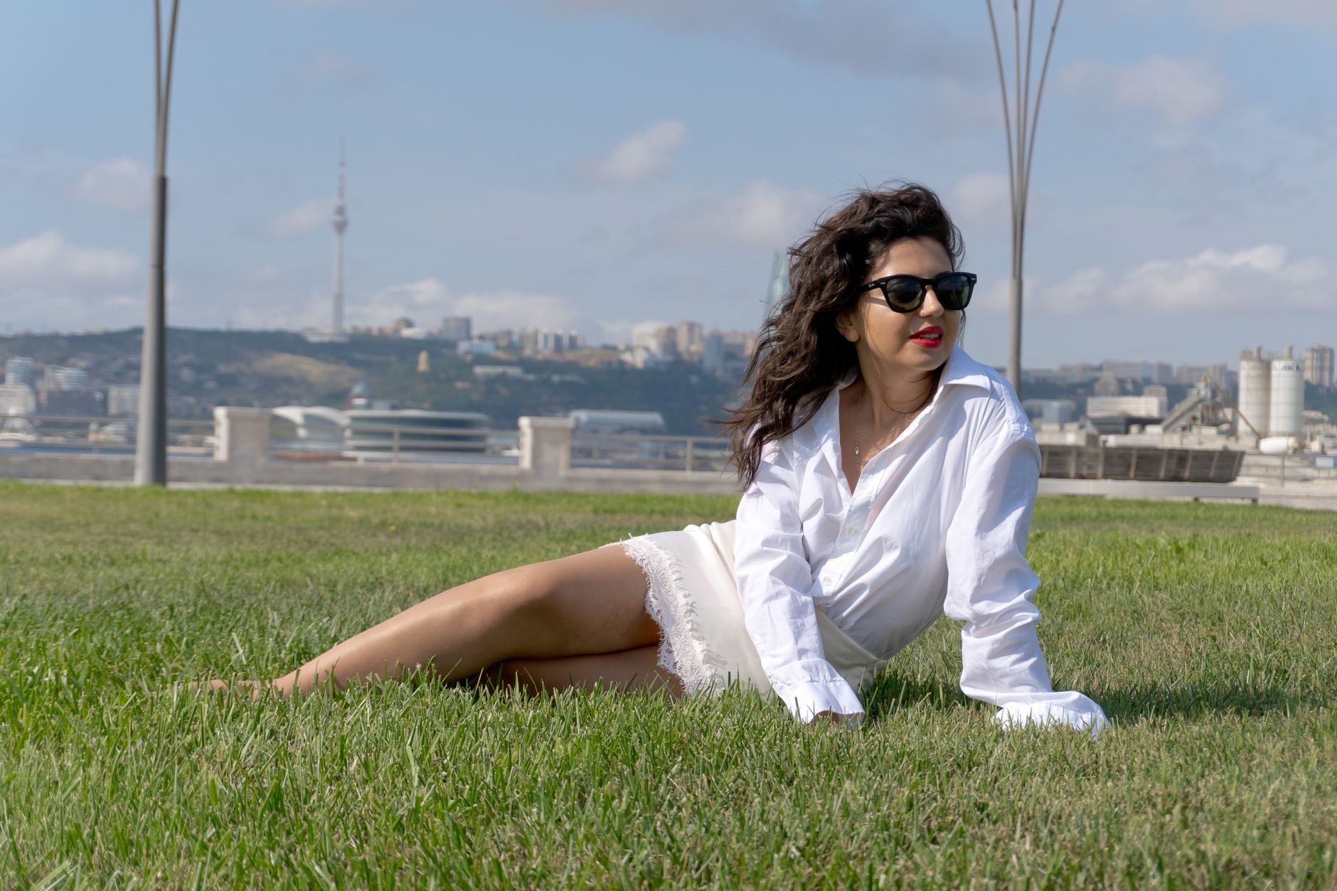 Woman wearing a white cotton midi skirt styled with a tucked linen shirt and leather sandals