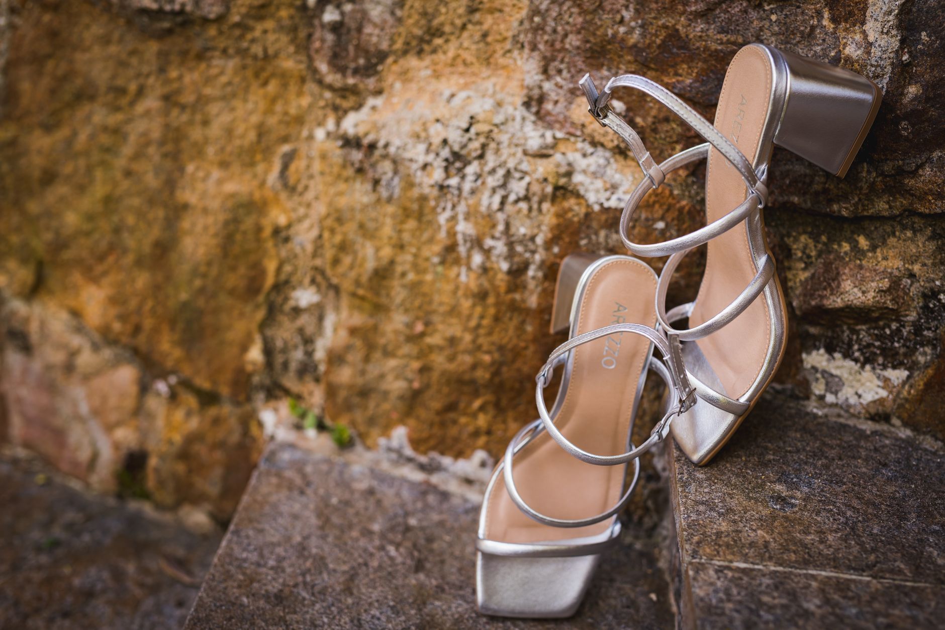 Detail shot of a bow-detailed sandal strap against a neutral surface